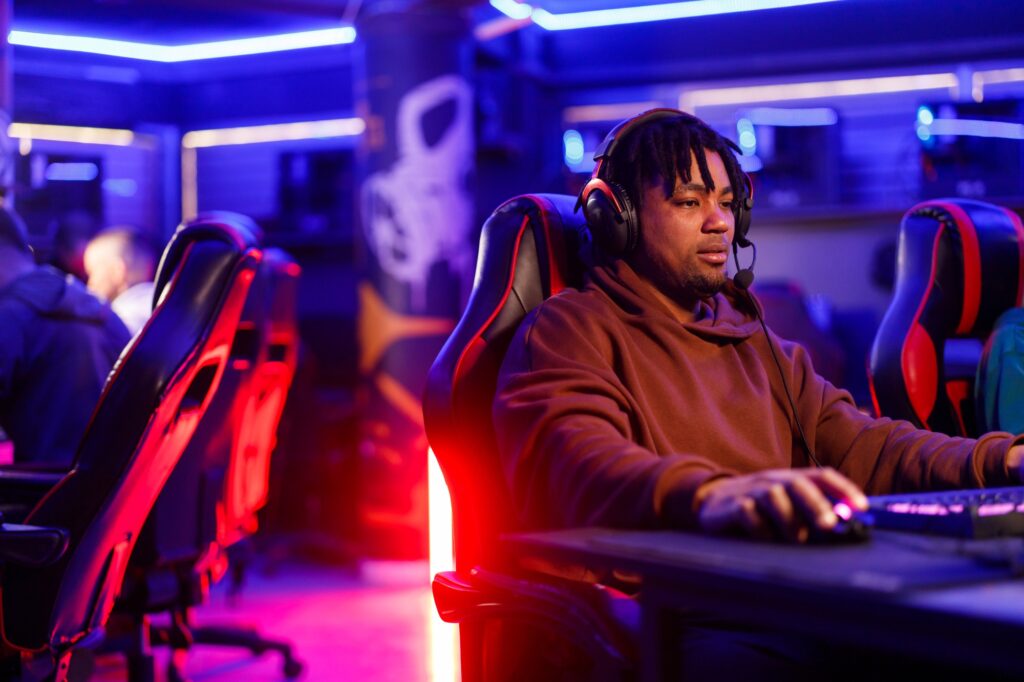 African american man with dreadlocks playing a video game in a gaming lounge